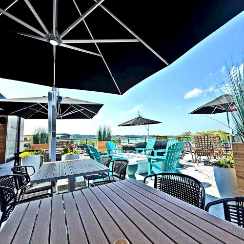 An outdoor patio with tables, chairs, and umbrellas under a clear sky.