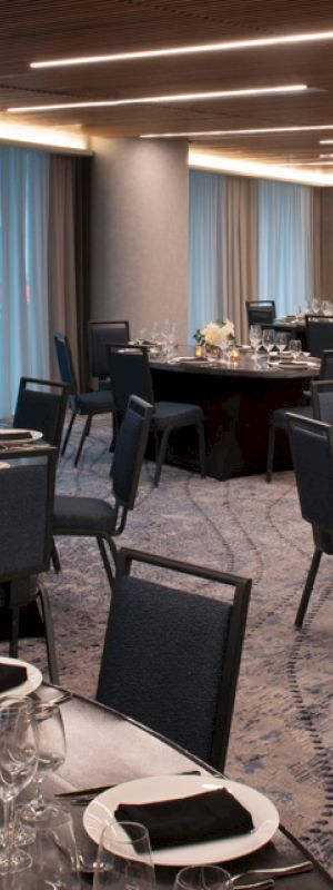 This image shows a banquet hall with round tables set for a formal event, featuring elegant tableware and centerpieces under ambient lighting.