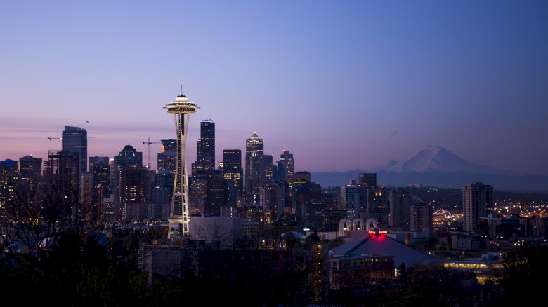Seattle skyline at dusk with the Space Needle visible and Mount Rainier in the background, creating a picturesque urban scene.